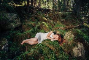 Beautiful woman sleeping in fairytale green forest