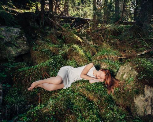 Beautiful woman sleeping in fairytale green forest